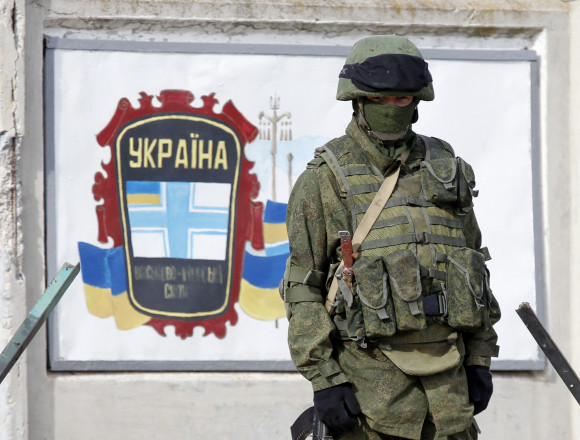 A uniformed man stands guard near a Ukrainian military base in the village of Perevalnoye