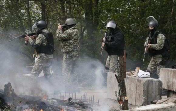 Ukrainian security force officers walk past a checkpoint set on fire and left by pro-Russian separatists near Slaviansk