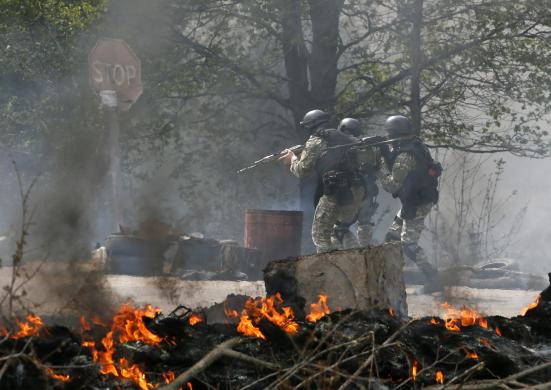 Ukrainian security force officers  walk past a checkpoint set on fire and left by pro-Russian separatists near Slaviansk