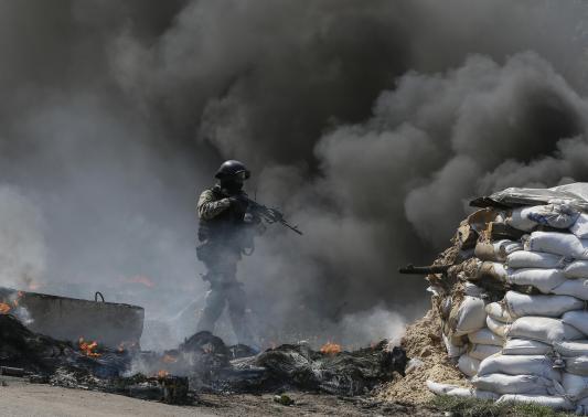 A Ukrainian security force officer is deployed at a checkpoint set on fire and left by pro-Russian separatists near Slaviansk